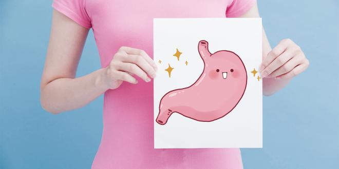 A woman holding an illustration of a happy stomach