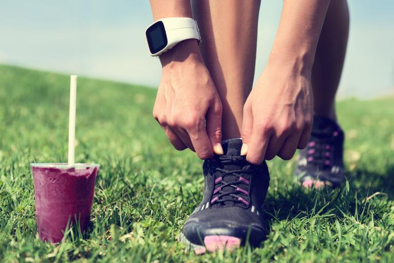 an athlete tying their shoes before running, with a beetroot smoothie